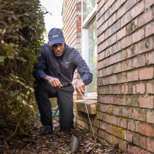 A Ja-Roy pest control technician checks the foundation of a residential home for pest activity