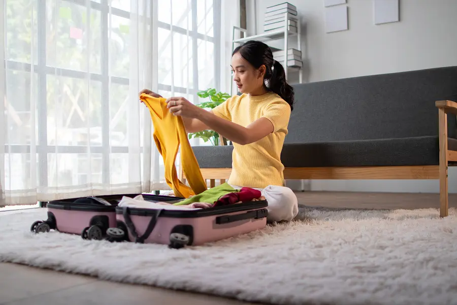 A college student unpacking her suitcase after returning home from school. Travelers and college students are especially at risk of getting bed bugs.
