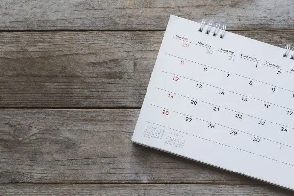 A white calendar on a wooden table - Keep pests away form your home with Ja-Roy Pest Control in Louisiana