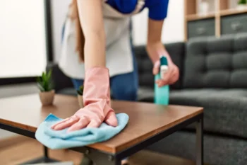 A Louisiana homeowner wiping down their coffee table after spraying it with cleaning solution