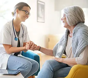 A doctor sits and holds an elderly patient's hands. Contact Ja-Roy Pest Control to protect your health care office from unwanted pests.