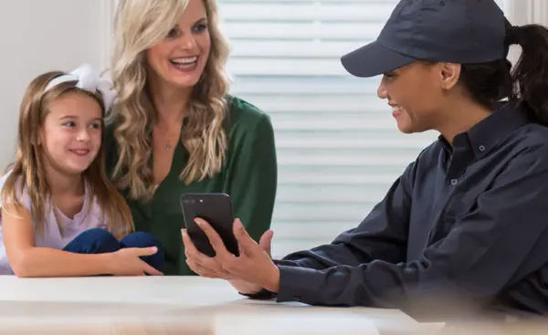 A Ja-Roy Pest Control technician shows a homeowner a customized pest protection plan on a smartphone