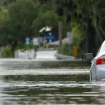 A residential road with cars sunken in high flood water.
