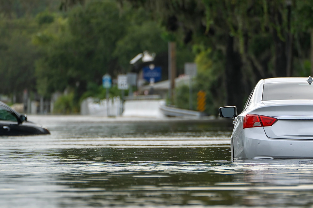 A residential road with cars sunken in high flood water.
